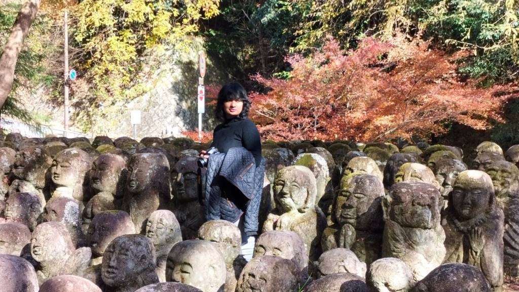 AWO journalist and writer, Ameena Navab, stands amidst the rakan statues of Otagi Nenbutsuji, the most unique temple 
in Kyoto, to photograph them Photo Credit: AWO staff